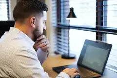 Tyler Costa reviewing real estate details on a laptop